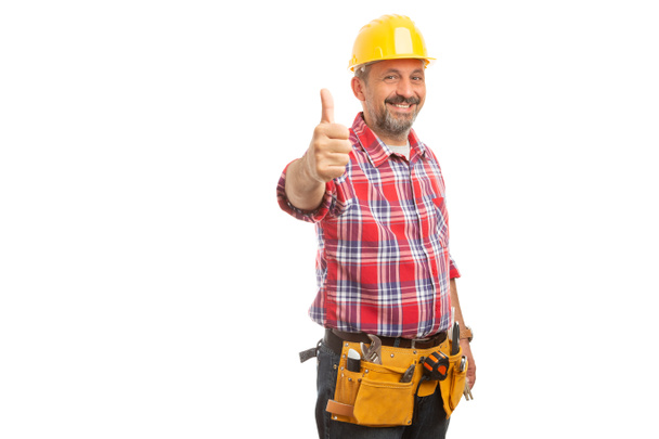 Männlicher Bauarbeiter hält Daumen hoch wie Geste mit gelbem Hut und Werkzeuggürtel auf weißem Hintergrund - Foto, Bild