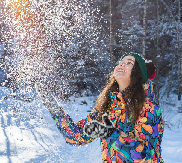 Feliz invierno mujer divertida lanzando bandera de nieve. Panorama cultivo de estilo de vida al aire libre chica jugando en la nieve al aire libre riendo en abrigo amarillo, sombrero, guantes y bufanda
. - Foto, imagen
