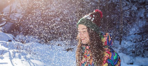 Щаслива зимова весела жінка кидає сніговий банер. Панорамний урожай вуличного способу життя дівчина грає в снігу зовні сміється в жовтому пальто, капелюсі, рукавичках і шарфі
. - Фото, зображення
