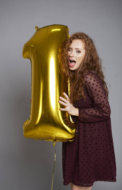 Jonge vrouw met gouden ballon viert eerste verjaardag haar bedrijf - Foto, afbeelding