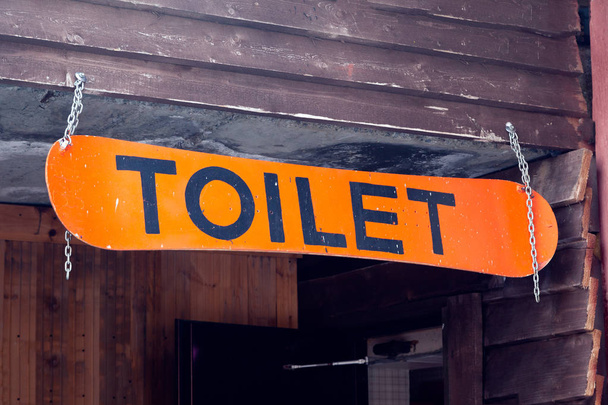 Orange snowboard z napisem WC w formie znak z wskaźnik, który jest zawieszony na łańcuszki srebrne w kawiarni w ośrodku narciarskim. Koncepcja, napis - Zdjęcie, obraz