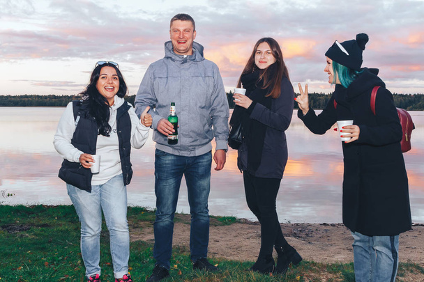September, 29, 2018 - Minsk, Belarus: Quest on sights of Belarus, group of people with drinks standing in front of lake in evening - Photo, Image
