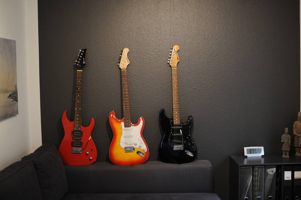 Three electric guitars of different colors on the couch - Foto, Imagen