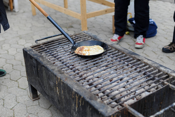 Process of cooking pancakes on frying pan on bonfire during carnival - Photo, Image