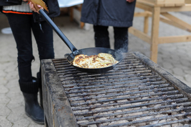 Processo di cottura di frittelle su padella per friggere in falò durante carnevale
 - Foto, immagini