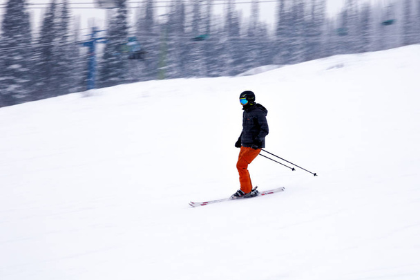 Russia, Sheregesh 2018.11.18 Professional skier in bright sportswear and outfit skiing downhill in snowy sunny high mountains. Blur, soft focus, object in motion. Concept of safe rest - Foto, Imagen