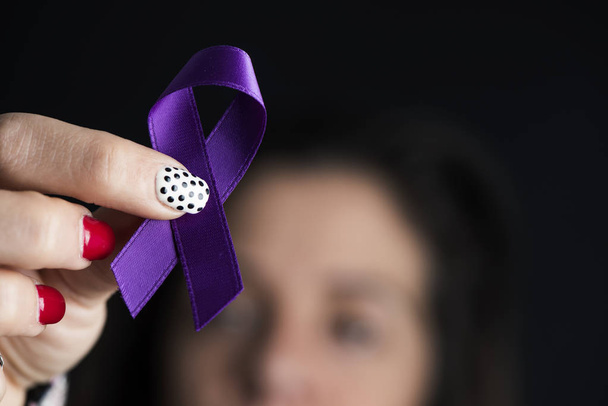 крупним планом молода біла жінка з фіолетовою стрічкою за усвідомлення неприйнятності насильства щодо жінок
 - Фото, зображення