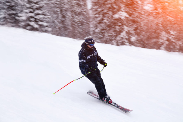 Russia, Sheregesh 2018.11.18 Professional skier in bright sportswear and outfit skiing downhill in snowy sunny high mountains. Blur, soft focus, object in motion. Concept of safe rest - Foto, Bild