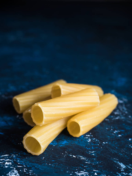 Dry pasta Tortiglioni closeup on a dark blue background. Front view, space for text - Zdjęcie, obraz
