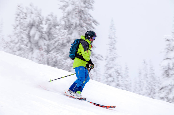 Rusland, Sheregesh 2018.11.18 professionele skiër in heldere sportkleding en outfit skiën afdaling in besneeuwde zonnige hoge bergen. Blur, soft focus ondervraagt object in beweging. Concept van veilige rust - Foto, afbeelding