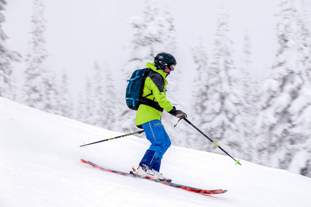 Russia, Sheregesh 2018.11.18 Professional skier in bright sportswear and outfit skiing downhill in snowy sunny high mountains. Blur, soft focus, object in motion. Concept of safe rest - Photo, Image