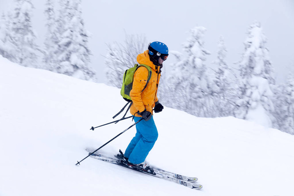 Ρωσία, Sheregesh 2018.11.18 επαγγελματίας σκιέρ σε φωτεινό αθλητικά είδη και στολή σκι κατάβασης στο χιονισμένο sunny ψηλά βουνά. Θαμπάδα, μαλακή εστίαση, το αντικείμενο σε κίνηση. Έννοια των ασφαλών υπόλοιπο - Φωτογραφία, εικόνα