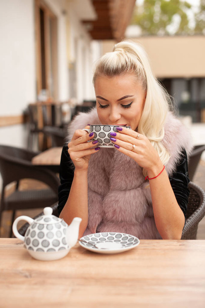 Beautiful young woman drink tea on bar terace in early autumn . - Fotó, kép