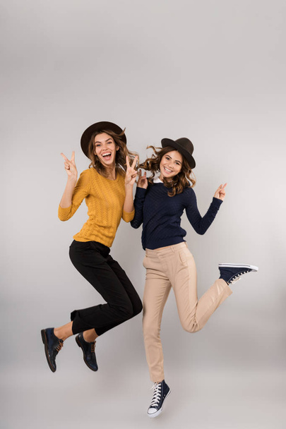 Full length image of two gorgeous girls smiling and having fun together isolated over gray background - Фото, зображення