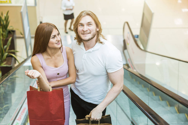 Kaunis nuori eurooppalainen rakastava pari, joka kantaa ostoskasseja ja nauttii yhdessä
. - Valokuva, kuva