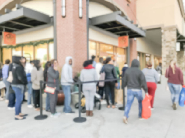 Θολή αφηρημένη μακρά σειρά των πελατών περιμένει στην είσοδο για μόδα κατάστημα ανοιχτό κατά τη διάρκεια της μαύρης Παρασκευής outlet mall, το Τέξας, ΗΠΑ. Defocused διακοπές ψώνια φόντο, αναδιπλούμενη ζώνη στύλου - Φωτογραφία, εικόνα