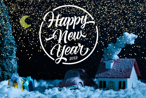 close-up shot of toy car with christmas gifts and house covered with snow at night, with "happy new year 2019" lettering - Photo, Image