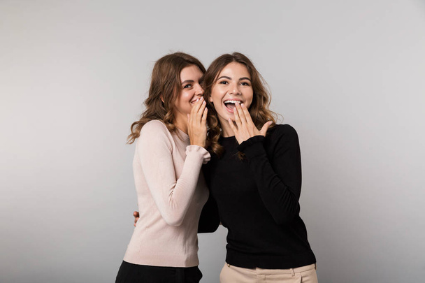 Зображення двох дівчат брюнетки посміхаються і позують разом ізольовано на сірому фоні
 - Фото, зображення