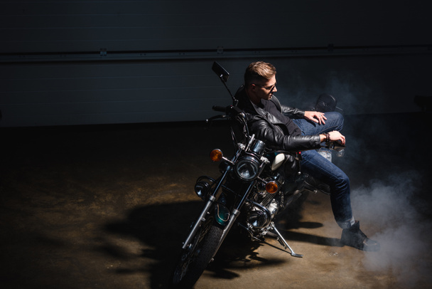 motociclista clásico en gafas de sol negras sentado en motocicleta en el garaje
 - Foto, imagen