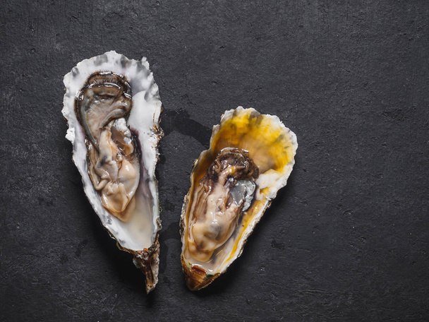 Raw oysters in shells on the black table. - Foto, imagen
