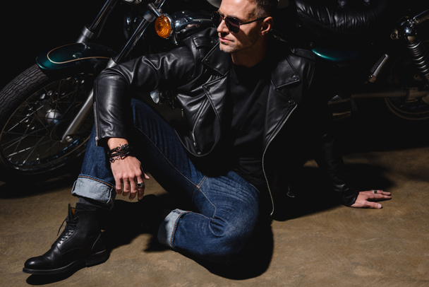 man in black sunglasses sitting by motorcycle in garage - Photo, Image