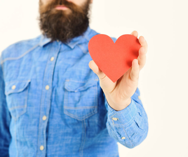 Man with beard holds red paper heart in hand, defocused. - Fotografie, Obrázek