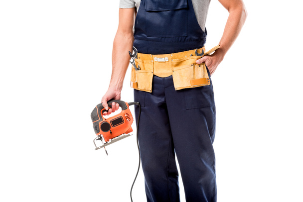 cropped view of carpenter with tool belt holding electric fret saw isolated on white - Foto, immagini