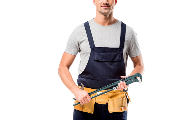 cropped view of worker in overalls holding pipe wrench isolated on white - Fotografie, Obrázek