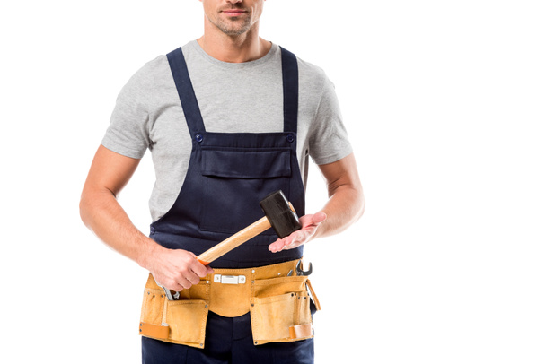 vista parcial del trabajador en overol sosteniendo martillo aislado sobre blanco
 - Foto, Imagen