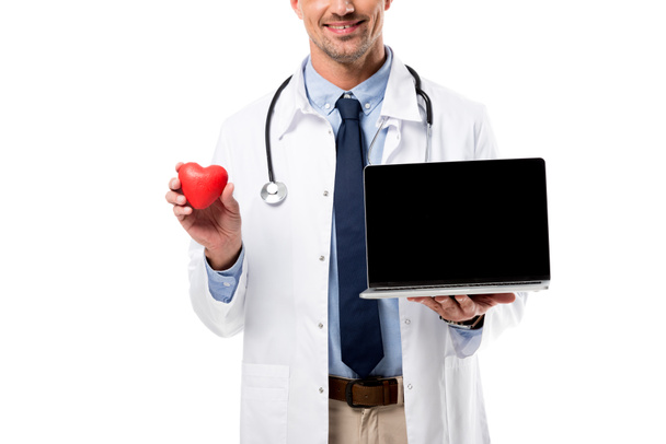 gedeeltelijke weergave van dokter hart model en laptop met leeg scherm geïsoleerd op wit, hart gezondheidszorg concept - Foto, afbeelding