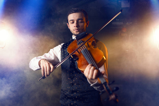 Portret van jonge mannelijke muzikant speelt viool, fiddler met muziekinstrument - Foto, afbeelding