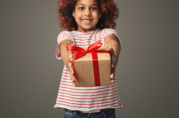 Black kid girl stretching out present box, selective focus - Foto, afbeelding
