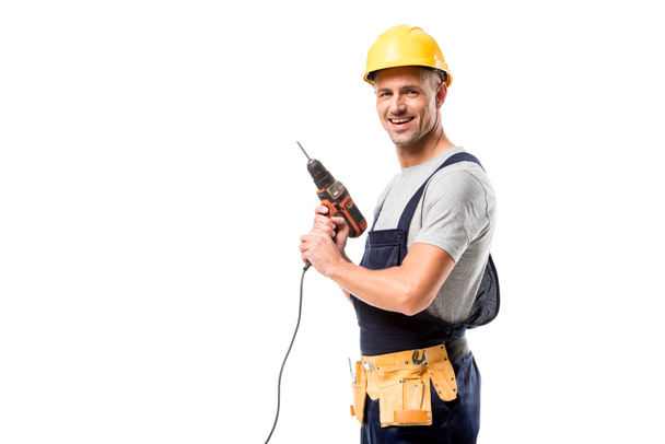 lachende bouwvakker in bedrijf boor geïsoleerd op wit helm - Foto, afbeelding