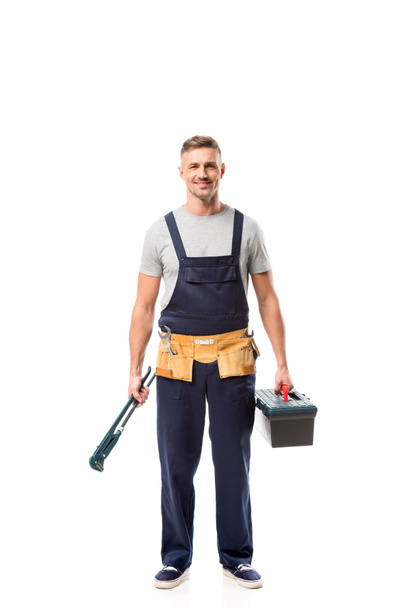 handsome worker holding pipe wrench and tool box isolated on white - Foto, Bild