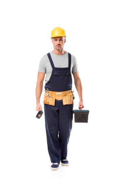 construction worker holding hammer, tool box and looking at camera isolated on white - Photo, Image