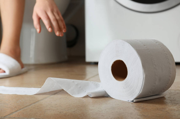 Woman making long arm for toilet paper on floor of restroom - Foto, Bild