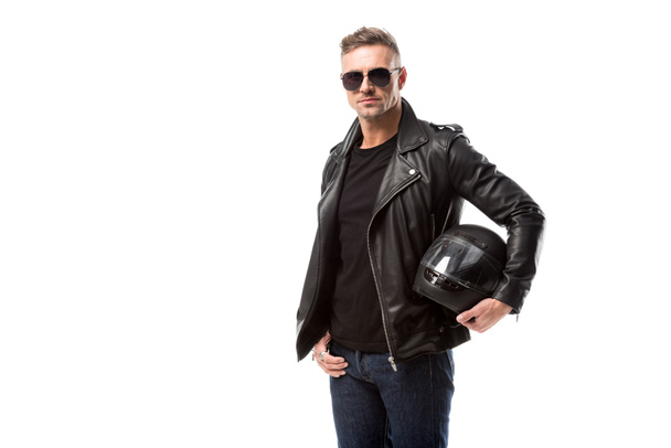 стильный мужчина в кожаной куртке и солнцезащитных очках с мотоциклетным шлемом изолирован на белом
 - Фото, изображение