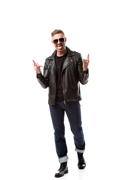excited stylish man in leather jacket showing rock signs and sticking out tongue isolated on white - Fotografie, Obrázek