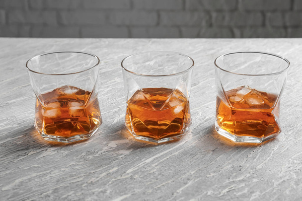Glasses of cold whiskey on light wooden table - Фото, изображение