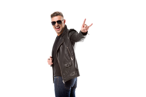excited man in leather jacket and sunglasses showing rock sign isolated on white - Foto, Imagen
