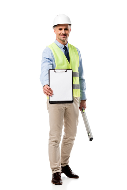 smiling engineer holding clipboard with blank sheet and spirit level isolated on white - Fotó, kép