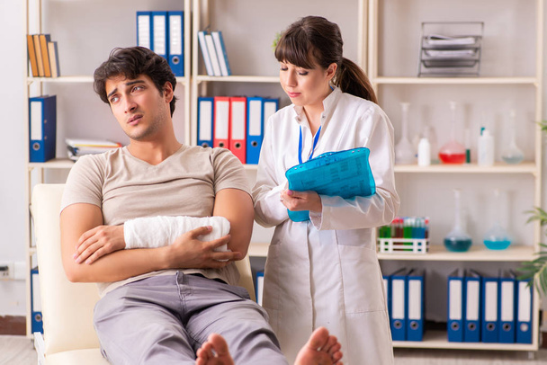 Young man with bandaged arm visiting female doctor traumatologis - Photo, Image
