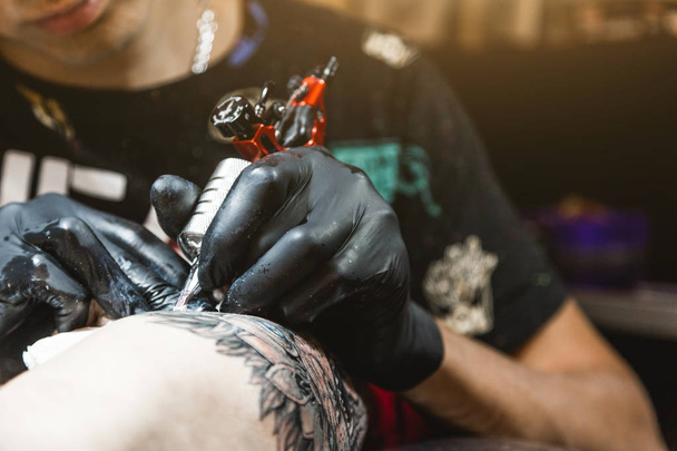 The tattoo artist creates a picture on the body of a man. close-up of tattoo machines and paints - Foto, Imagem
