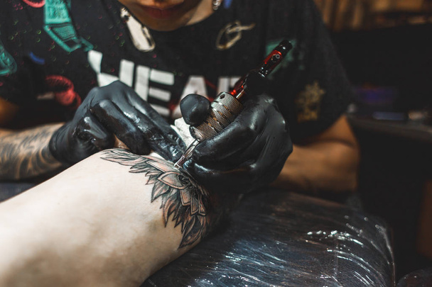 The tattoo artist creates a picture on the body of a man. close-up of tattoo machines and hands - Foto, imagen