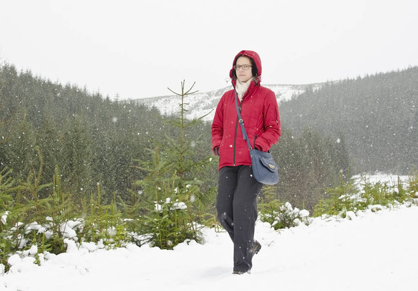 Nuori nainen punaisessa takissa kävely aikana on lunta sää - Valokuva, kuva