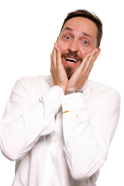 Portrait d'un beau jeune homme dérangé en chemise blanche tenant des paumes près de la joue
 - Photo, image