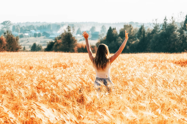 Young woman in wheat field. View from the back - Foto, Imagen