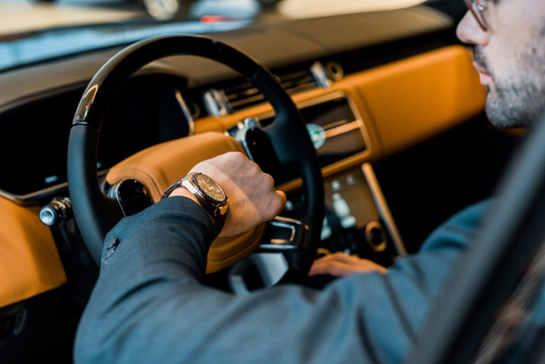 partial view of businessman checking watch in luxury car - 写真・画像