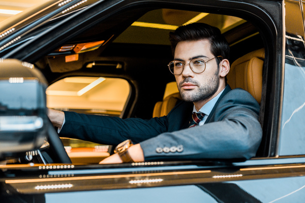 young stylish businessman in eyeglasses sitting in luxury car - Φωτογραφία, εικόνα