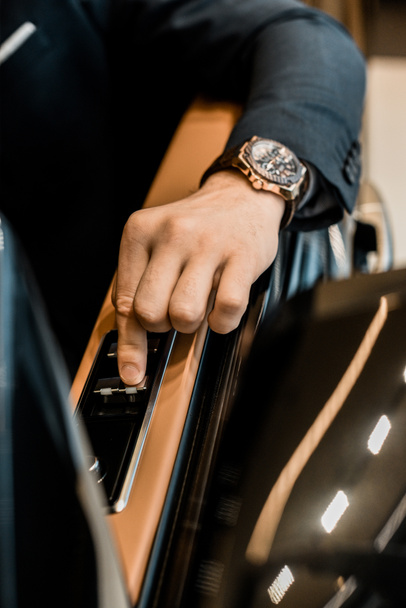 cropped image of businessman with luxury watch pushing button for closing window of automobile - Photo, Image